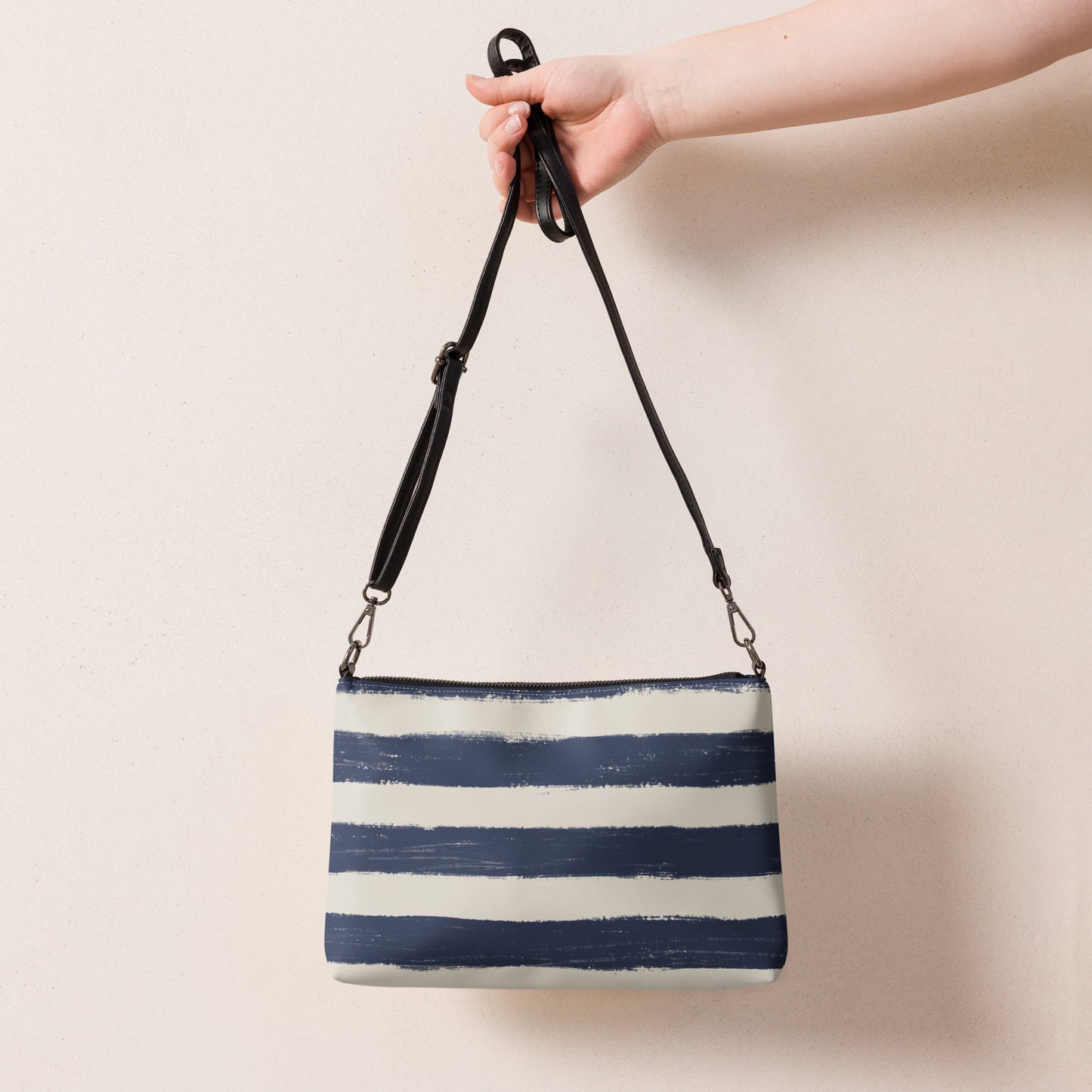 Breton stripe vegan leather crossbody bag with adjustable strap, held by hand for scale and detail