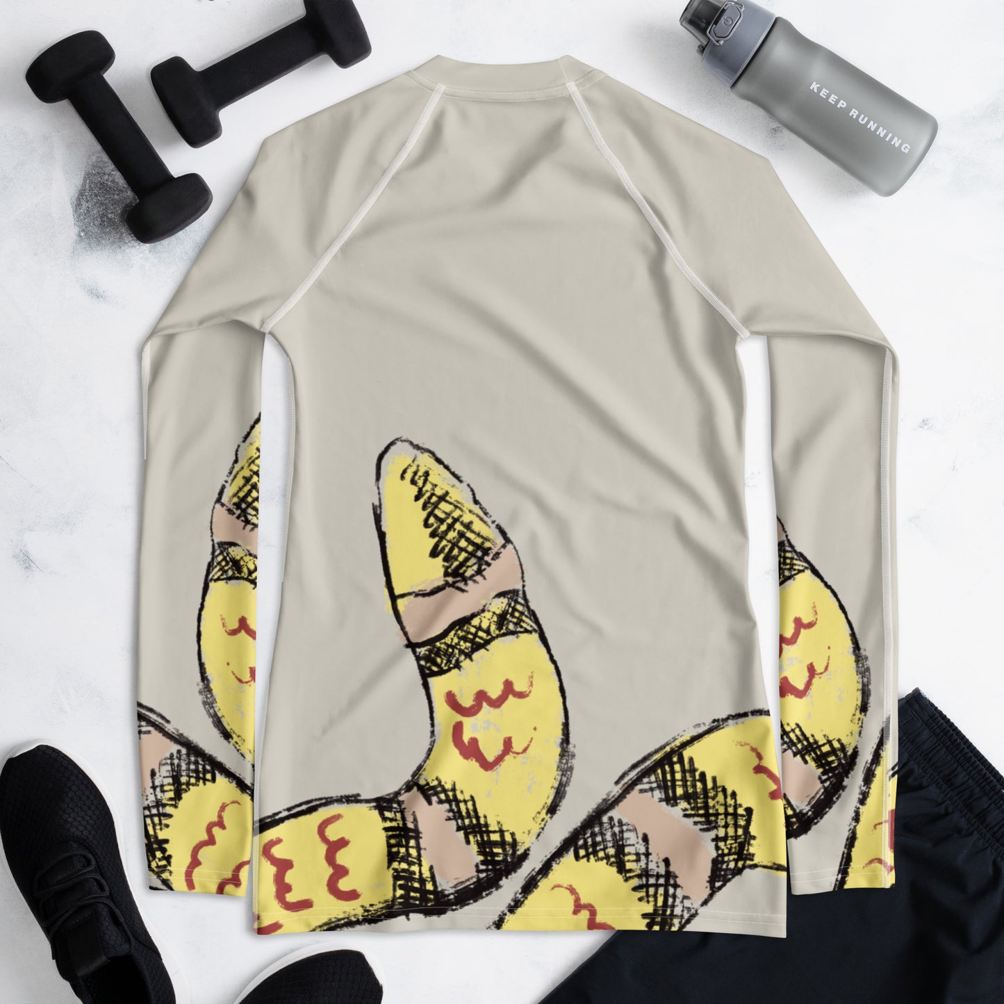 Flat lay of snake print women’s rash guard with gym gear, designed for workouts, yoga, and surf with sun protection.