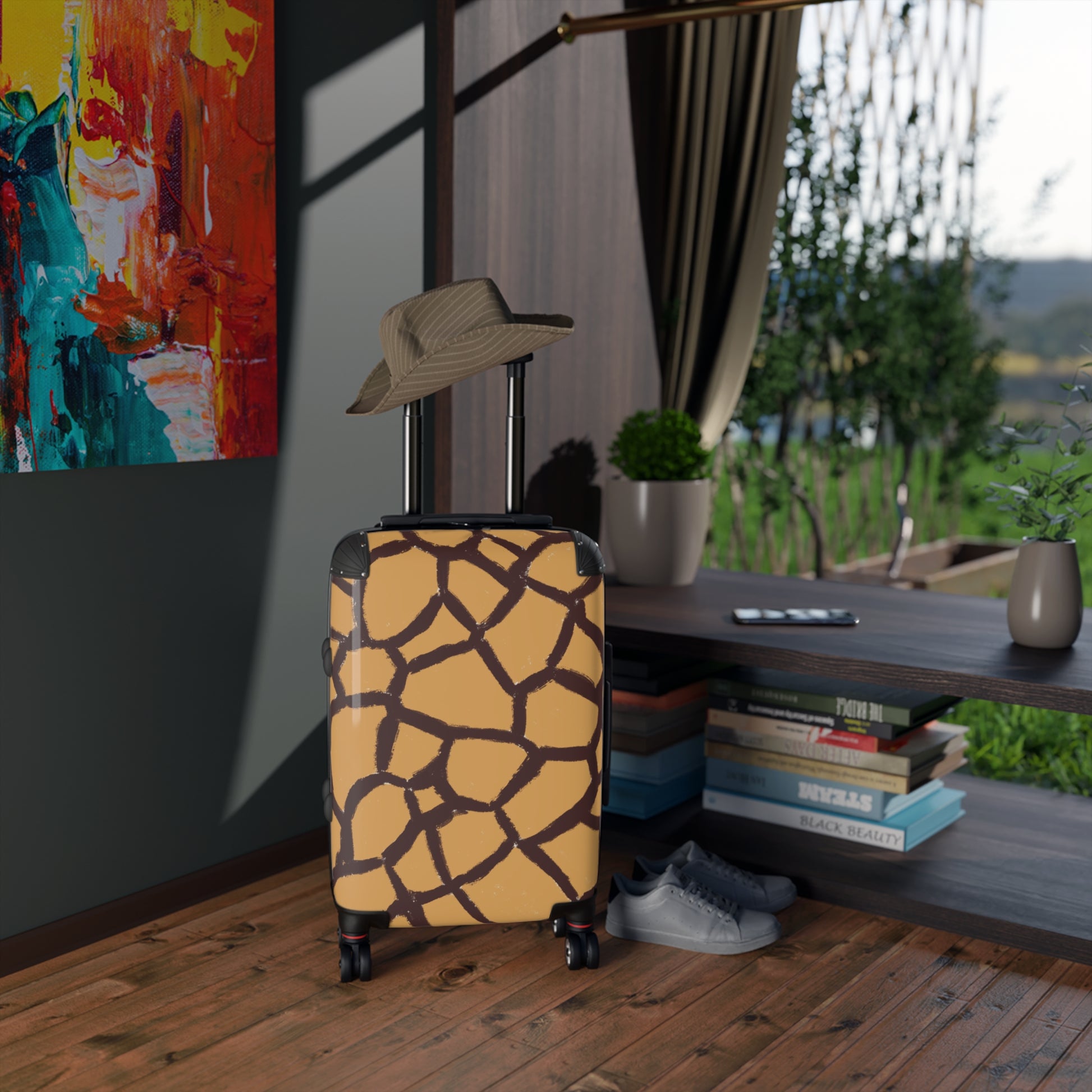 Giraffe pattern small luggage hard-shell carry-on by Panther & Palm placed in a stylish hotel room, for size context. 