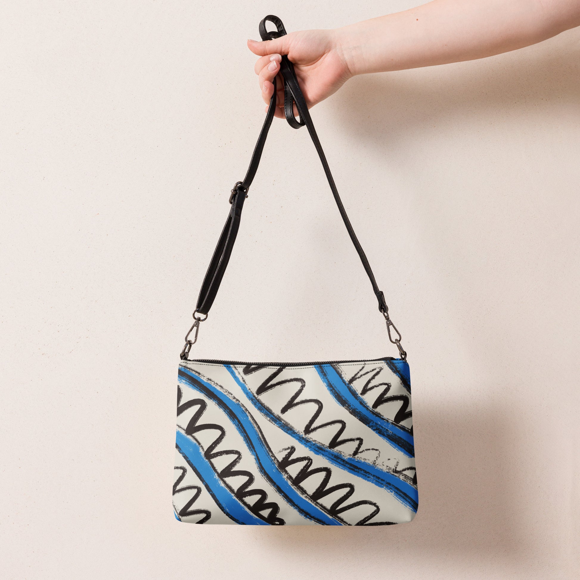 Blue and white stripe crossbody bag held by black adjustable strap, displayed against neutral background.