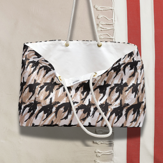 Top-down view of the open Houndstooth Sketch Tote with white lining, placed over a fringed towel for a relaxed summer vibe.